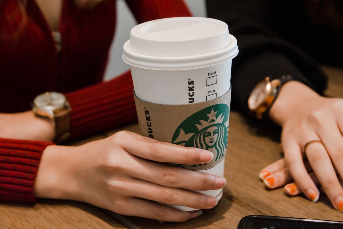 Person holding white Starbucks cup