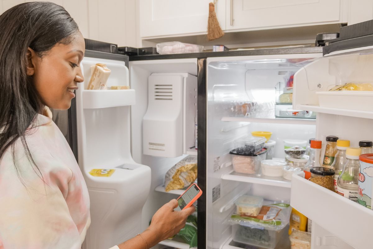 Woman holding a cellphone in front of fridge
