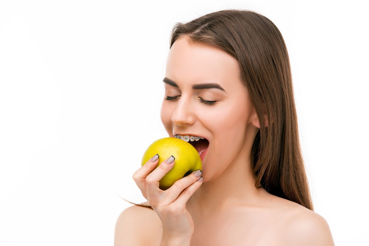 Young woman with braces eating apple